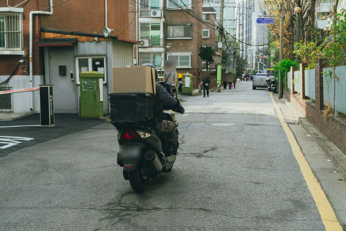 상자를 실은 배달 이륜차가 서울 주택가 골목을 달리는 뒷모습